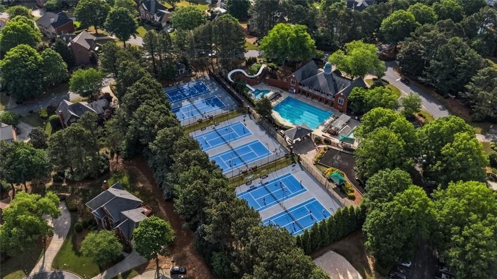 Aerial view of Cambridge's tennis and pickleball courts, the pool and surrounding wooded home sites