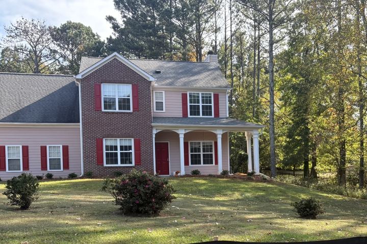 Front exterior of 1325 Greenwood Acres Drive, a two-story home with red shutters and a front porch