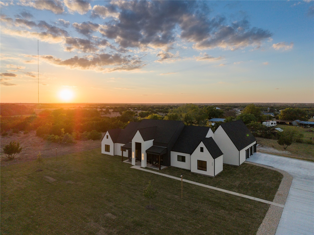 A wide-angle shot of a sprawling 2-acre backyard in Liberty Hill at golden hour, showing a covered patio and native Texas landscaping